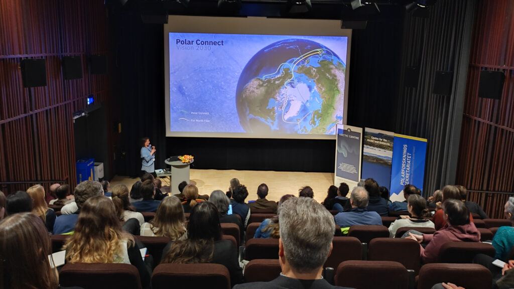 Woman standing and presenting in a lecture hall.